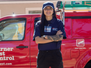 Turner pest control professional in front of red work truck