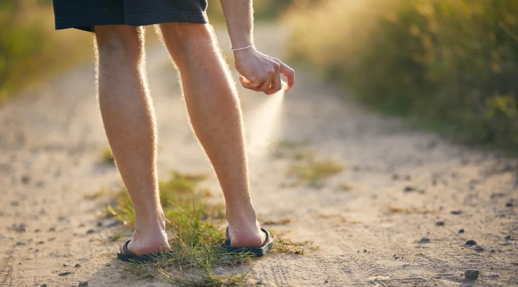 person spraying legs with mosquito repellent picture for blog titled how do you stop mosquitoes from biting you